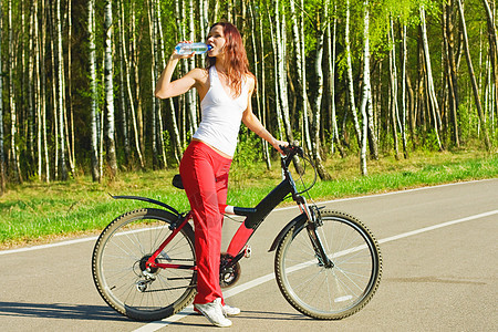 骑自行车的妇女踏板冒险树木旅行瓶子女人衣服女孩活动青少年图片