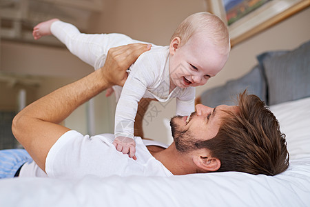 父亲和儿子的时光 一个父亲躺在床上抱着他的女婴在空中图片