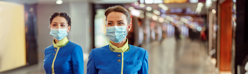 在机场携带旅行邮袋的戴医疗面具的女医务人员图片