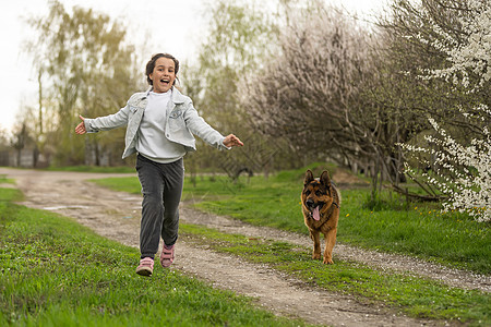 小女孩带着狗在花花园里跑步童年孩子动物娱乐微笑猎犬友谊朋友公园街道图片