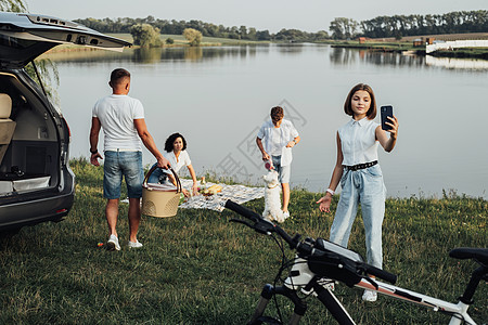 快乐的四位成员家庭享受周末旅行 Minivan汽车 青少年女儿在湖边与宠狗玩耍时自以为是(Minivan Car)图片