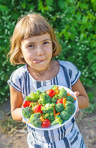 儿童吃蔬菜花椰菜和胡萝卜 有选择性的焦点沙拉孩子们童年盘子饮食厨房午餐食物围裙女孩图片