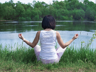 一个女孩坐在河边的草地上 背着一个冥想姿势灵魂网络温泉脉轮瑜伽水平运动生活训练活力图片