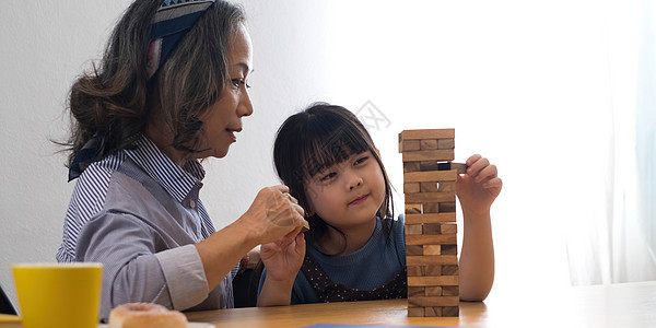 小女孩和外婆在家玩Jenga游戏玩具享受儿子女儿成人教育孙女祖父祖父母祖母图片