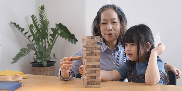 亚洲祖母和孙女一起玩Jenga建筑师的欢乐时光 在家为孩子们开展休闲活动 笑声成人客厅乐趣童年儿子祖父闲暇女士祖父母女儿图片