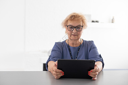 快乐成熟的中年女性在家里使用数字平板电脑度过闲暇时光 性格开朗的现代高级女士拿着电脑 看有趣的电影和笑声 休闲和科技理念会议奶奶图片