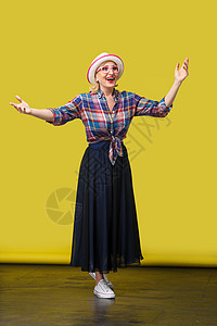 时尚的中年妇女 在黄色背景下从事临时作风衬衫格子奶奶露齿手臂享受幸福冒充舞蹈乐趣图片