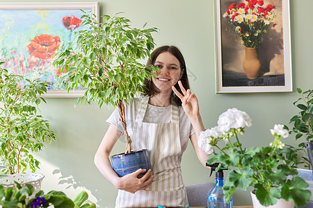 美丽的笑笑少女的肖像 与陶瓷植物图片