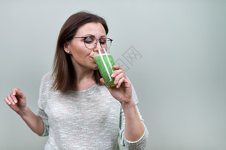 成熟的女子 喝绿色蔬菜冰凉水 健康的素食饮食 妇女饮果汁图片