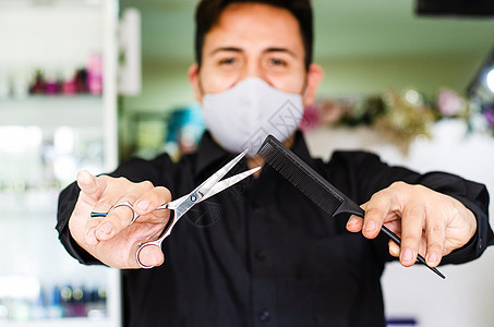 一个漂亮的理发师的画像 一个戴着安全面具的人 手里拿着剪刀和一把梳子 社交距离 预防流行病病毒的措施图片
