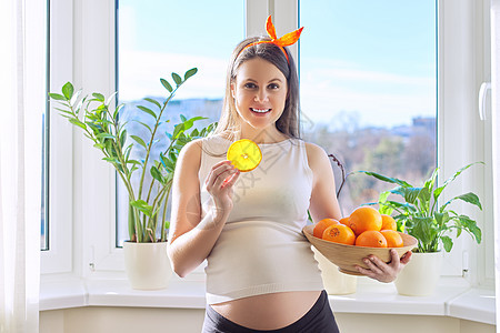 健康的维他命食物 美丽的 快乐的有橙子的怀孕年轻女性营养食物微笑水果妈妈幸福肚子婴儿女孩腹部图片