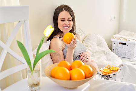 带橙子的年轻美丽的怀孕少女 在家坐在床上睡觉母性水果饮食女孩身体腹部成人肚子婴儿母亲图片
