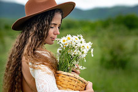 怀着白裙子和棕帽子的中年妇女手里握着一束盛大的花朵 祝贺之野花花瓣花束季节生活天空荒野甘菊植物乡村雏菊图片