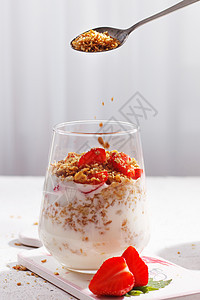 格拉诺拉种子被倒在杯子上 加草莓酸奶 健康早餐 垂直照片图片