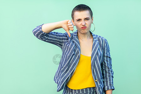 有情感的年轻女性 短发有浅绿色背景的厌恶失败女士愤怒拇指批判西装衬衫商务鬼脸图片