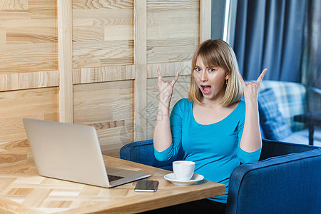 穿着蓝衬衫 坐着并从事计算机工作的情感劳动妇女女性手指摇杆人士岩石手势工人技术商务业者图片