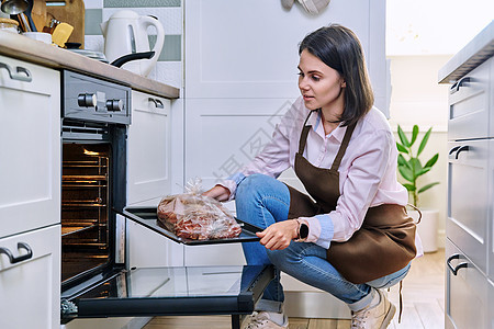 在烤盘上吃肉的年轻女子 开炉 家里厨房女士食物火炉烘烤女性炊具闲暇主妇成人烹饪图片