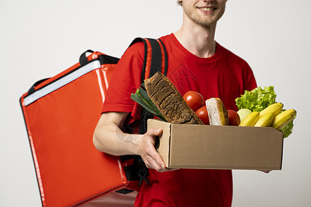 食品运输 职业和人的概念 快乐的笑脸送货员带着满是蔬菜和热袋的胡椒盒 背着白底皮肩膀图片