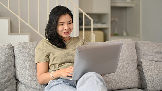 穿着散衣在互联网上冲浪 在家里笔记本电脑上读新书的迷人的女性女性图片