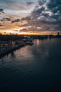 日落时的城市风景与大河流在前方 背景是暴云图片
