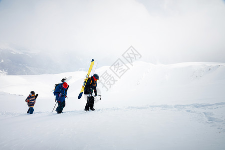 三个玩滑雪的朋友滑雪者上山 用雪板和滑雪机在他们的手中为后国或搭便车而跳雪游览登山旅行远足国家季节高山假期滑雪板粉末图片