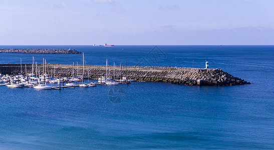 上面有灯塔和停泊游艇的断水池蓝色旅游旅行海岸汽艇地标假期天空游客港口图片