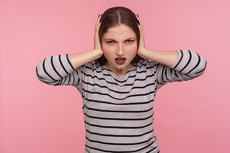 粉红色背景的黑发年轻女性的情感肖像噪音女孩警报手指失败女士耳朵压力头痛疼痛图片