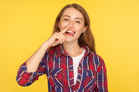 黄色背景的年轻情感女性的肖像女士鼻屎感染采摘女孩舌头手指鼻子钻孔鬼脸图片