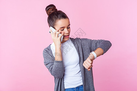 穿粉红色背景衣服的情感少女讲话会议手表小时检查发型女孩黑发青少年电话图片