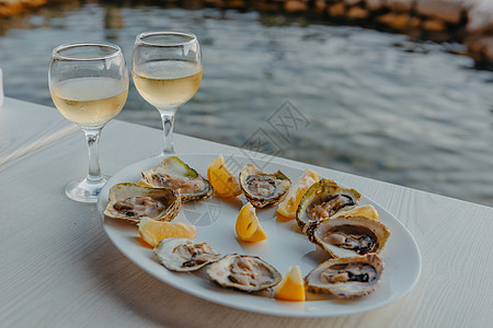 新鲜捕获的牡蛎放在盘子和藤蔓眼镜上 位于黑山牡蛎养殖场附近的科托尔湾沿岸的餐厅 海鲜 美丽的海景 牡蛎养殖场和山脉 亚得里亚海景图片