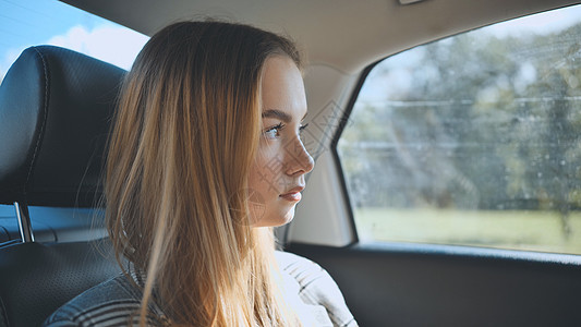 一个年轻女孩坐在后座的汽车里女性乘客交通出租车旅行运输服务享受人士土地图片