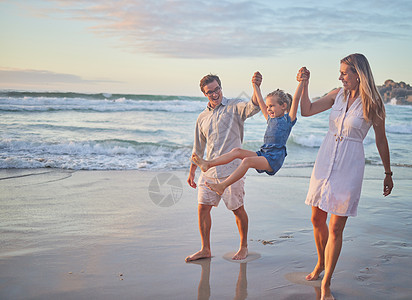 可爱的小女孩与父母手牵着手荡秋千 年轻的白人妈妈和爸爸与他们的女儿手牵着手 在沙滩上散步时抱着她 夏日阳光下的家庭乐趣孩子们孩子图片