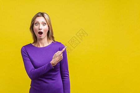 黄色背景的情感美丽的女人震惊惊喜广告胜利大眼睛优胜者成功手指紫色女士图片