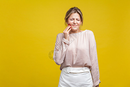 黄色背景的情感美丽的女人衬衫牙科牙疼疾病女士女性保健伤害头痛金发女郎图片