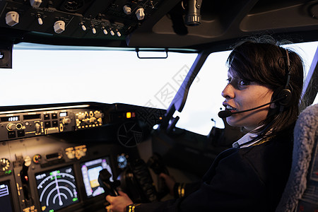 使用仪表板上的电开关驾驶飞机喷气机的年轻副副驾驶图片