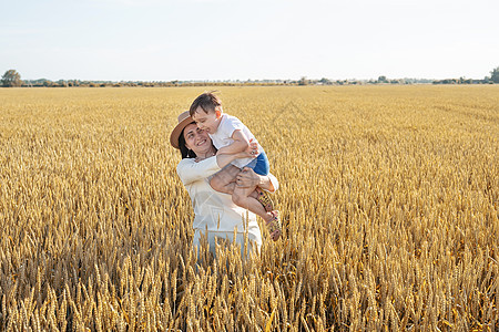 母亲和婴儿在小麦田上行走的幸福家庭女士父亲童年农业男人闲暇女性男性天空太阳图片