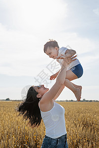 母亲和婴儿在小麦田上行走的幸福家庭收成孩子父母日落太阳快乐妈妈男生女士农业图片