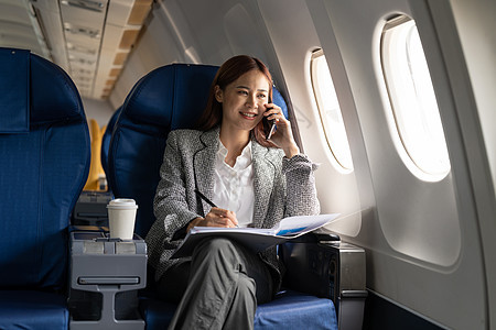 年轻迷人 成功的亚洲商业女性坐在他的私人商务飞机的椅子上打电话和工作图片