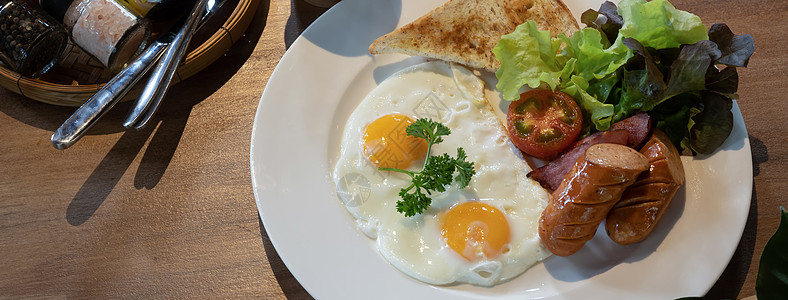 英国早餐 炸鸡蛋 烤培根 吐司 香肠和木制桌上的新鲜沙拉图片
