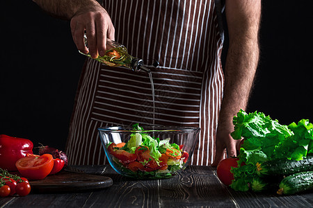 烹饪与家庭概念     特写男性手在碗里加橄榄油的沙拉厨师饮食食物成人男人盘子厨房勺子木板蔬菜图片