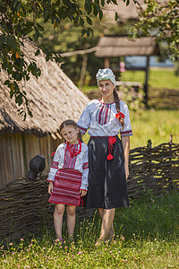 母亲和女儿在围栏附近父母服装建筑微笑村庄妈妈新闻业女性服饰文化图片