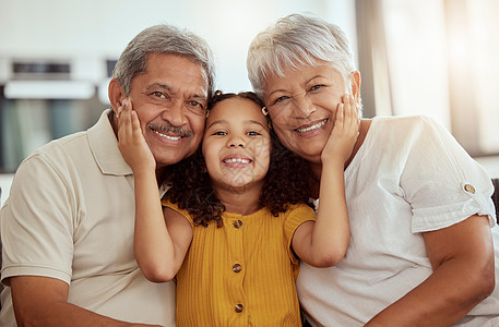 混合种族的祖父母与孙女在家里的客厅里享受周末的肖像 微笑的西班牙裔女孩与祖母和祖父融为一体 坐在一起的愉快的前辈和孩子图片
