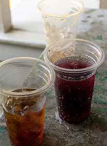 软饮料和可支配塑料玻璃杯中的冰红色饮料甜水杯子玻璃汽水野餐橙子桌子果汁图片