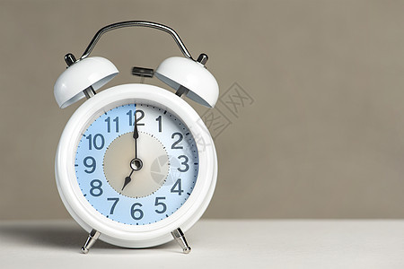 七点闹钟 一个白色的闹钟在一张白色的桌子上 时钟指针指向 7 点 时间更改为夏令时或冬令时 设置 7 00 或 19 00 的闹图片