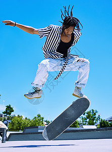 酷年轻 时尚的非洲裔美国男孩在滑板公园的滑板上表演滑板技巧 专注的年轻人在公园外面的滑板上表演 ollies 享受滑冰的严肃的人图片