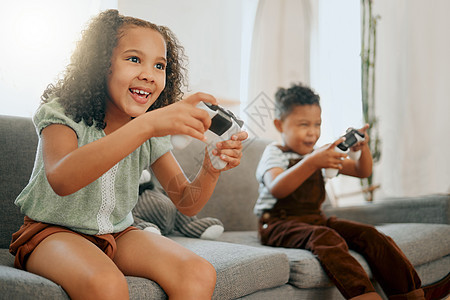 两个快乐的混血兄弟姐妹在休闲沙发上一起放松 同时玩有趣的视频游戏 孩子们只有周末在家边打游戏边比赛图片