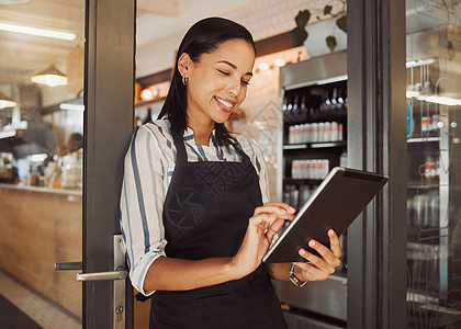 在她的餐厅使用数字平板电脑的女商务人士 咖啡馆老板在她的店门口使用在线应用程序 自信的企业主在她的杂货店使用无线设备图片