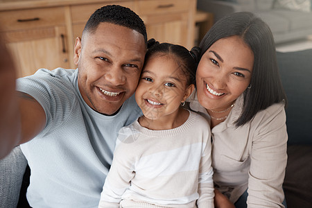 一个三口之家在家里的沙发上放松的肖像 爱的黑人家庭在沙发上亲热 年轻夫妇在家里与他们的女儿建立联系长椅自拍牙裔父亲乐趣男人男性母图片