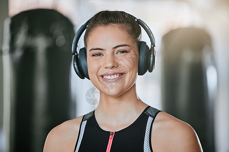 微笑的教练的画像独自在健身房里 戴着耳机听音乐 美丽快乐的白种人教练站在健身俱乐部锻炼期间 在运动健身中心进行常规训练的妇女图片