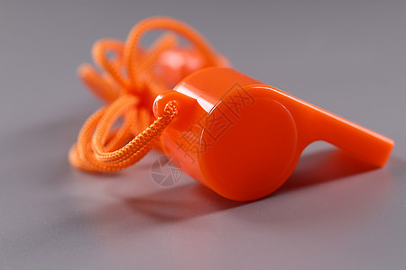 灰色背景带绳索的橙色塑料口哨配饰噪音法官警报警察信号玩具宏观运动阴影图片